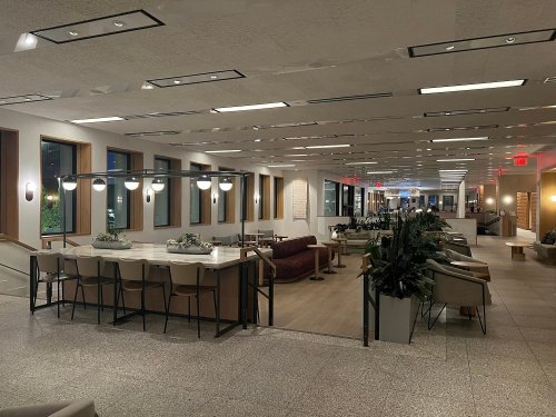Modern interior of a spacious lounge area with seating, plants, and bright lighting.