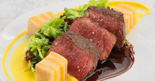 A white plate with cubes of cast iron steak artistically arranged