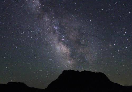 A starry night sky with the Milky Way visible above a dark mountain silhouette.