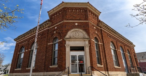 A U.S. flag flies above the red brick post office of Denison, Iowa, under a blue sky.