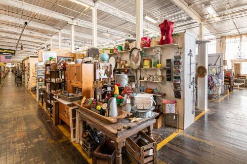 A vibrant antique shop aisle filled with various vintage items, furniture, and decor on display.