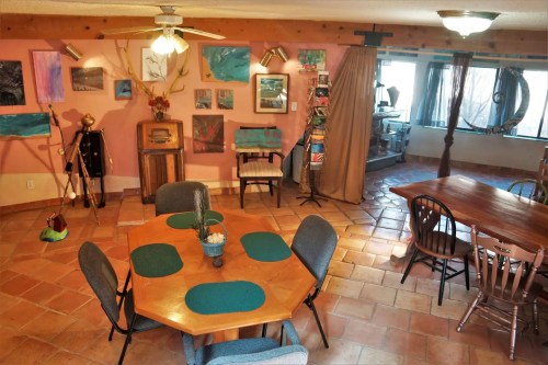 Cozy interior with a wooden dining table, chairs, and colorful artwork on the walls in a warm, inviting space.