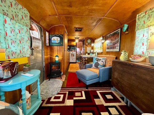 Cozy interior of a vintage trailer, featuring colorful decor, a small kitchen, and a comfortable seating area.