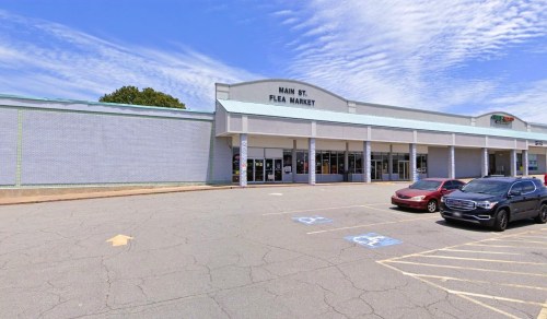 Exterior of Main St. Flea Market with a clear blue sky, featuring parked cars in front of the building.