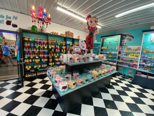 A colorful candy shop interior with jars of sweets, a large Betty Boop figure, and a checkered floor.