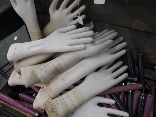 A pile of white rubber gloves with some marked lines, mixed with various colored tubes in a container.