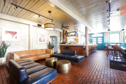 A stylish lounge area with leather sofas, round tables, and a bar, featuring warm lighting and a cozy atmosphere.