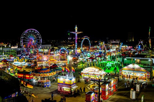 A vibrant night scene of a carnival with colorful lights, rides, and food stalls bustling with activity.