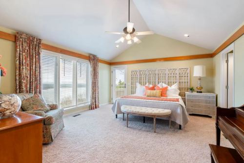 Spacious bedroom with large windows, a king bed, decorative pillows, and a cozy seating area.