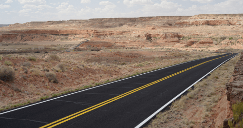 a paved road drives through the desert landscape outside tuba city, arizona, a small town perfect for a road trip