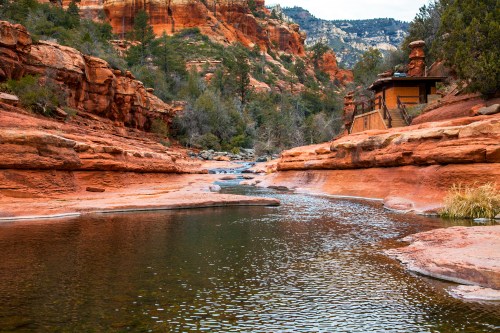a river runs through the red rock landscape at slide rock state park in sedona
