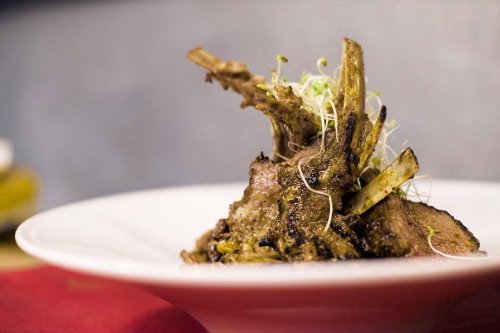 A beautifully plated dish featuring tender lamb chops garnished with sprouts on a white plate.