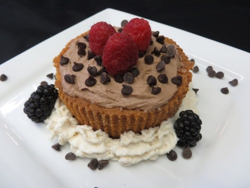 A chocolate mousse dessert in a graham cracker crust, topped with raspberries, chocolate chips, and blackberries.