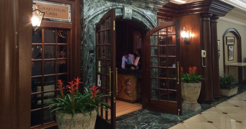 Entrance to the Charleston Grill, featuring double doors, elegant decor, and potted plants.