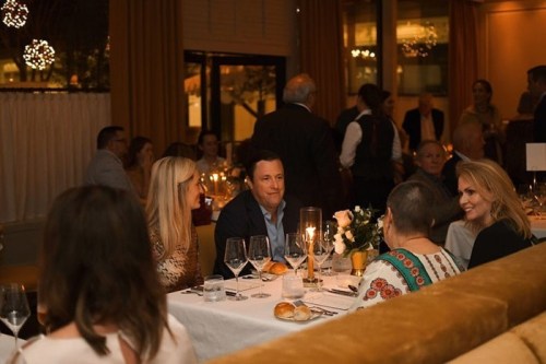 A lively restaurant scene with diners enjoying a meal, soft lighting, and elegant decor. Conversations and laughter abound.