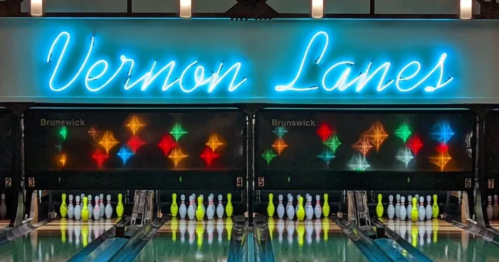 Neon sign reading "Vernon Lanes" above colorful bowling pins and a vibrant bowling alley backdrop.