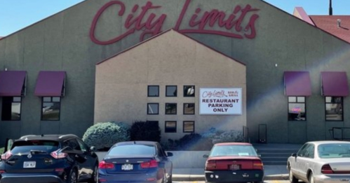 A building with "City Limits" sign, featuring a parking area for a restaurant, and several parked cars in front.