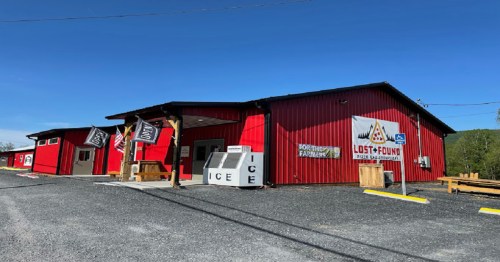 Red building with "Lost & Found" sign, open for business, featuring an ice vending machine outside. Gravel parking area.