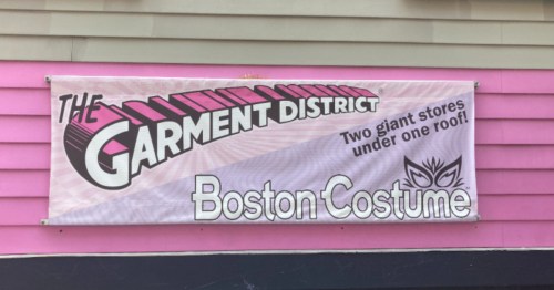 a banner sign for the garment district in cambridge massachusetts tacked onto a pink building