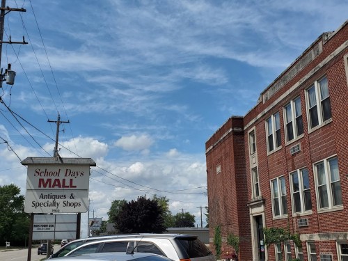 A brick building with a sign for "School Days Mall" and a clear blue sky with scattered clouds.