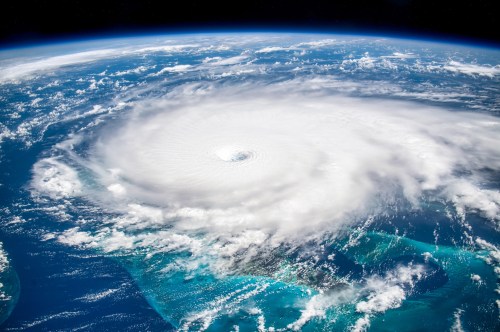 Aerial view of a powerful hurricane swirling over the ocean, surrounded by clouds and blue waters.