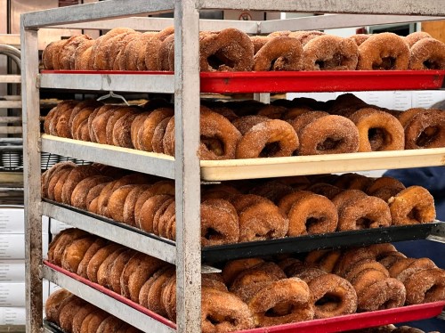 A metal rack filled with rows of freshly made, cinnamon-sugar coated donuts.
