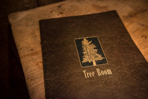 A menu titled "Tree Room" with a tree illustration, resting on a wooden surface.