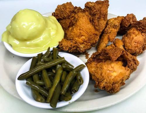 A plate of fried chicken, green beans, and a scoop of yellow custard dessert.