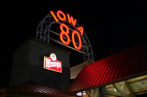 Sign for Iowa 80 with a Wendy's logo, illuminated at night.