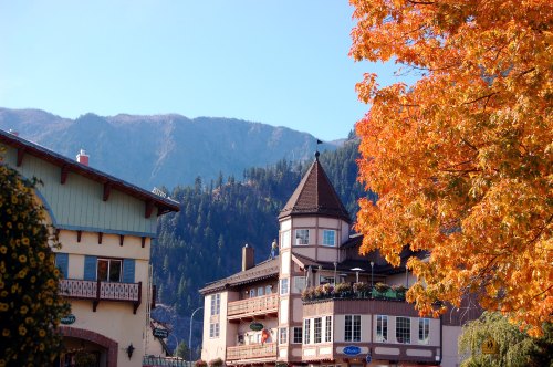 A charming alpine village with colorful autumn foliage and mountains in the background.