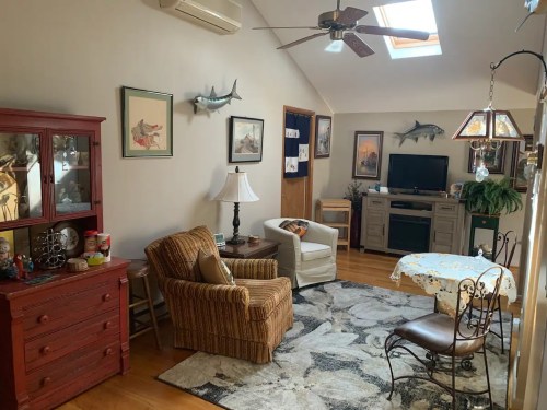 Cozy living room with a skylight, comfortable seating, a TV, and decorative fish on the walls.