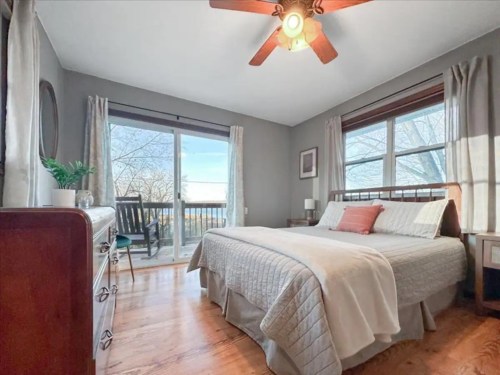 Cozy bedroom with a queen bed, wooden furniture, and large windows overlooking a scenic view.