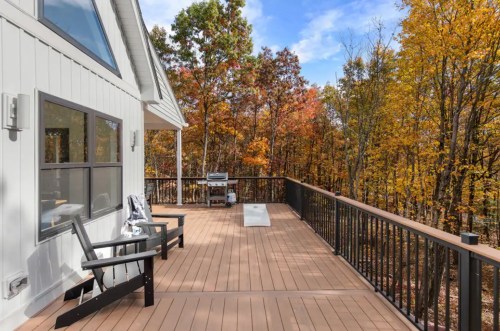 A spacious wooden deck with seating, surrounded by vibrant autumn trees and a clear blue sky.