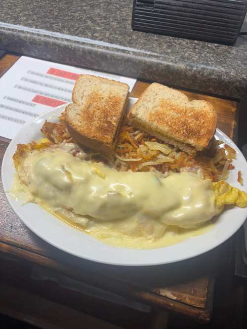 A plate with a cheesy omelet, hash browns, and two slices of toasted bread.
