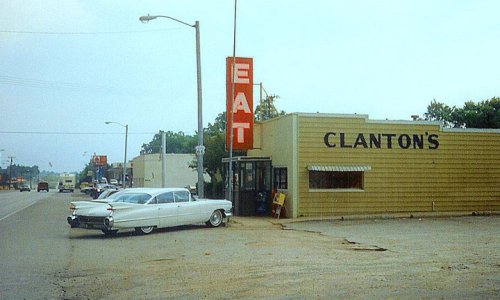 A vintage diner named Clanton's with a large "EAT" sign, featuring a classic white car parked outside.