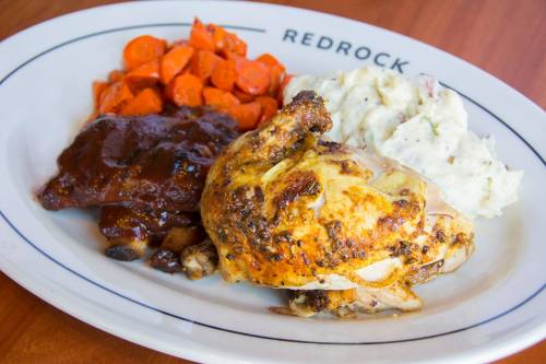 A plate featuring roasted chicken, barbecue sauce, mashed potatoes, and glazed carrots.