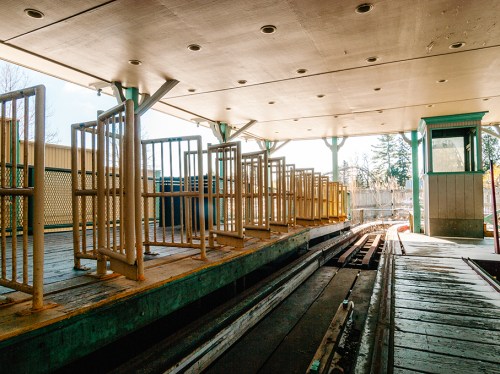 Abandoned train platform with empty turnstiles and a small booth, illuminated by natural light.