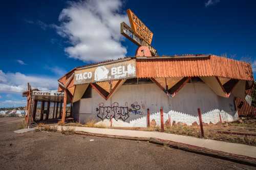 An abandoned Taco Bell building with striking white walls and a wooden-bordered roof.