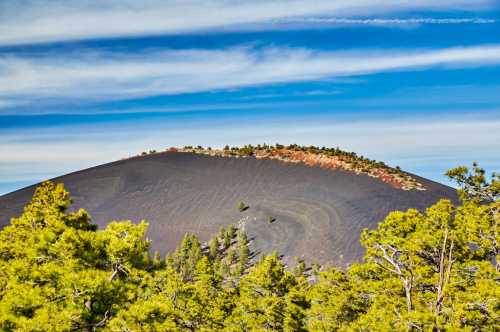 Once an active volcano, the cinder has been reduced to a fine powder and covers the face of the mountain with a dark black color which contracts the bright green trees in the foreground.