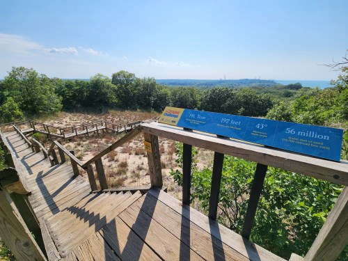 Wooden steps lead down to a scenic overlook with informational signs about Mt. Tom and the surrounding landscape.
