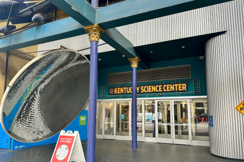 Entrance of the Kentucky Science Center, featuring a large reflective sculpture and colorful signage.