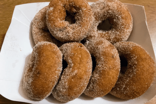 A plate of freshly made, sugar-coated donuts arranged neatly.