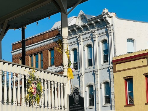 A view of historic buildings with decorative railings and a clear blue sky in the background.