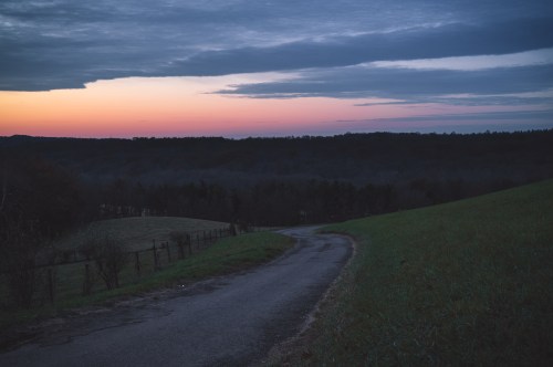 The sun rising over the hills of Malabar State Park, painting the sky pink and gray as the landscape is bathed in shadows.
