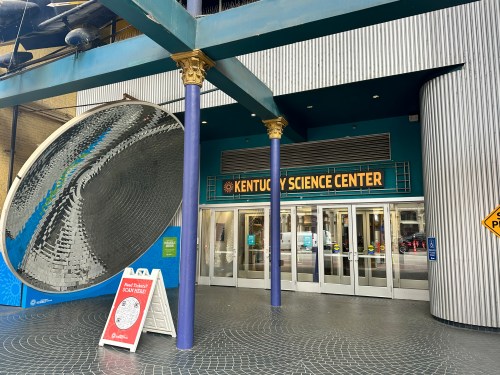 Entrance to the Kentucky Science Center, featuring a large reflective sculpture and colorful signage.