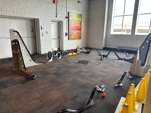 Indoor playground with a winding track, ramps, and colorful balls scattered on a carpeted floor.
