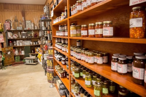 A cozy store interior with wooden shelves filled with various jars of preserves and canned goods.