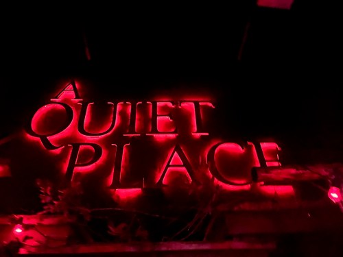 Neon sign reading "A QUIET PLACE" illuminated in red light against a dark background.