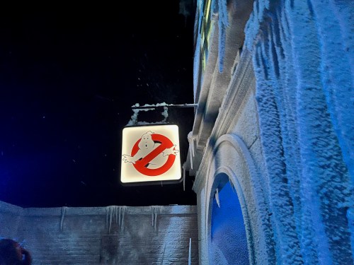 A glowing Ghostbusters sign hangs above a snowy, icy building at night.