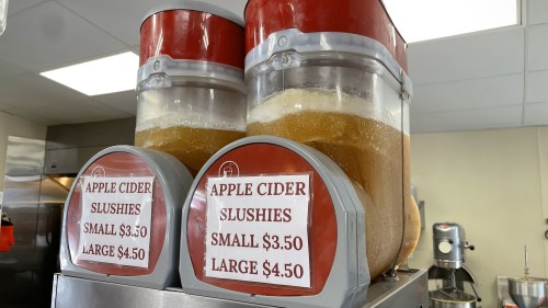 Two dispensers of apple cider slushies with price signs: small $3.30, large $4.50.